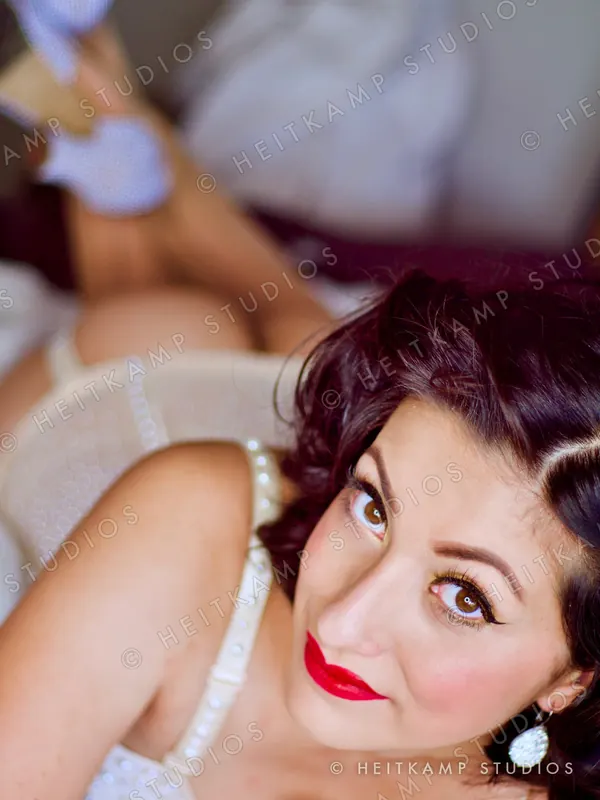 Close-up of Artemisa with red lips and vintage pin curls, looking up at the camera